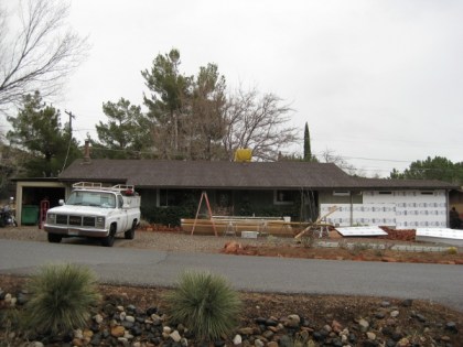 House with construction materials out front and some on the house